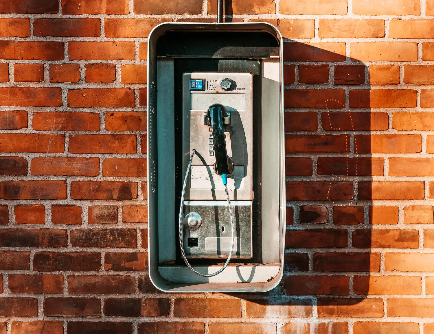 ONECOLOURS-CONTACT-US-PAYPHONE-ON-BRICK-WALL